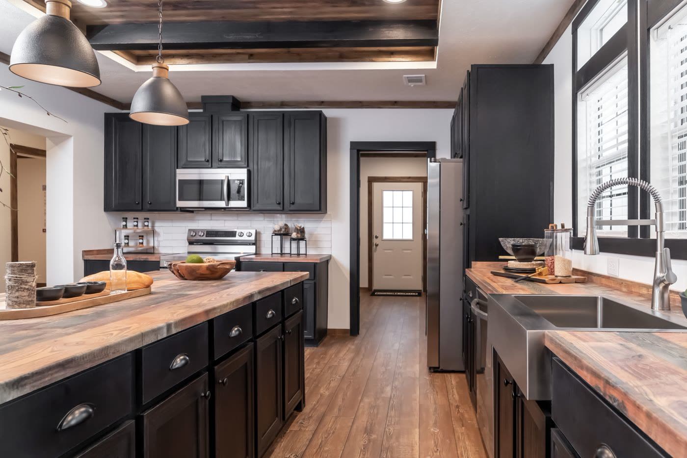 Kitchen toward the back door. Pendant lights over the island, range wall at left, sink at right.