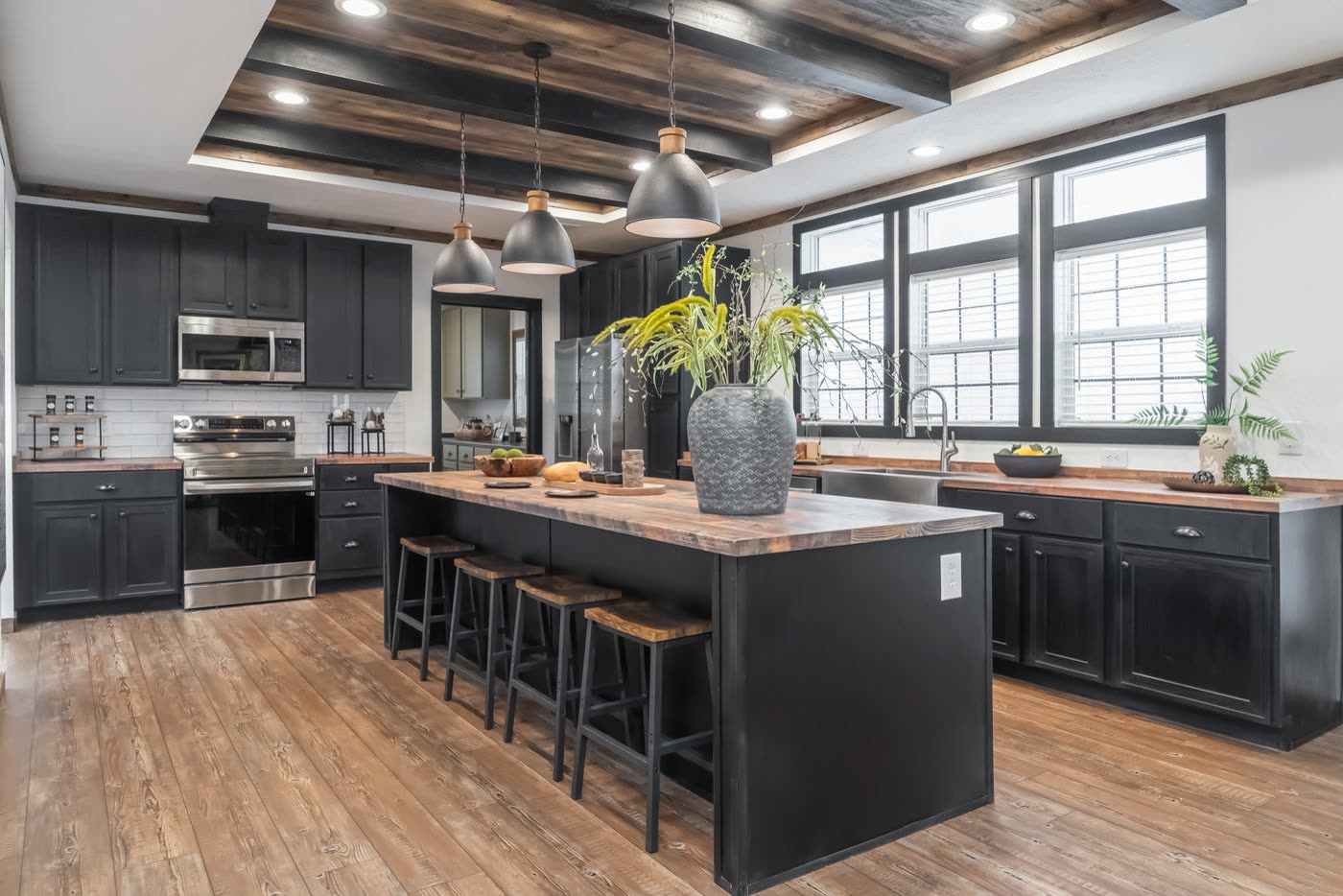 Kitchen. Island with stools, three pendants, triple window, beamed ceiling.