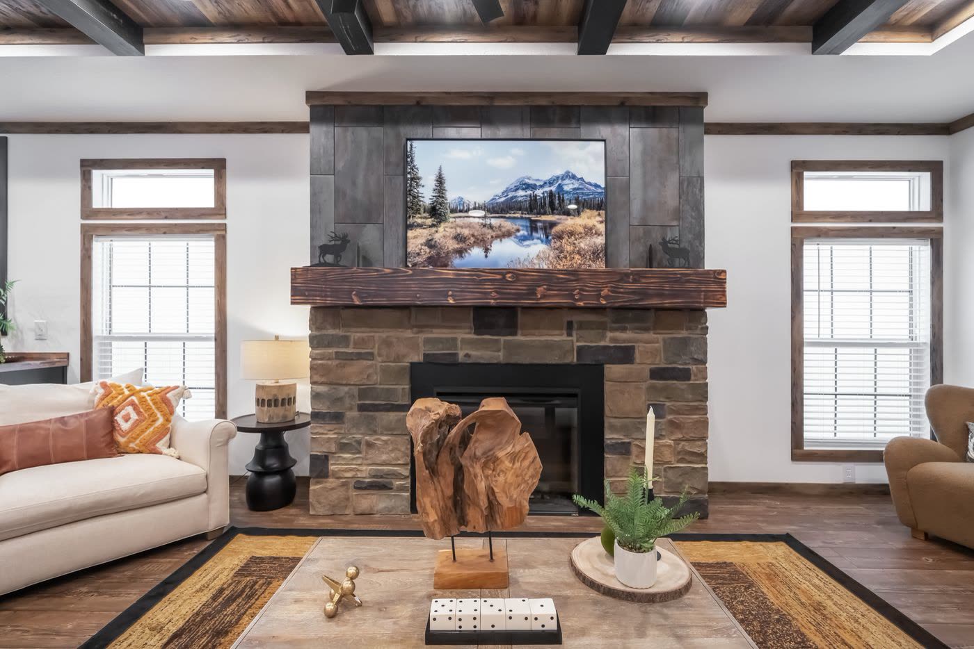 Living room. Stone fireplace with wood mantel and television, windows either side.