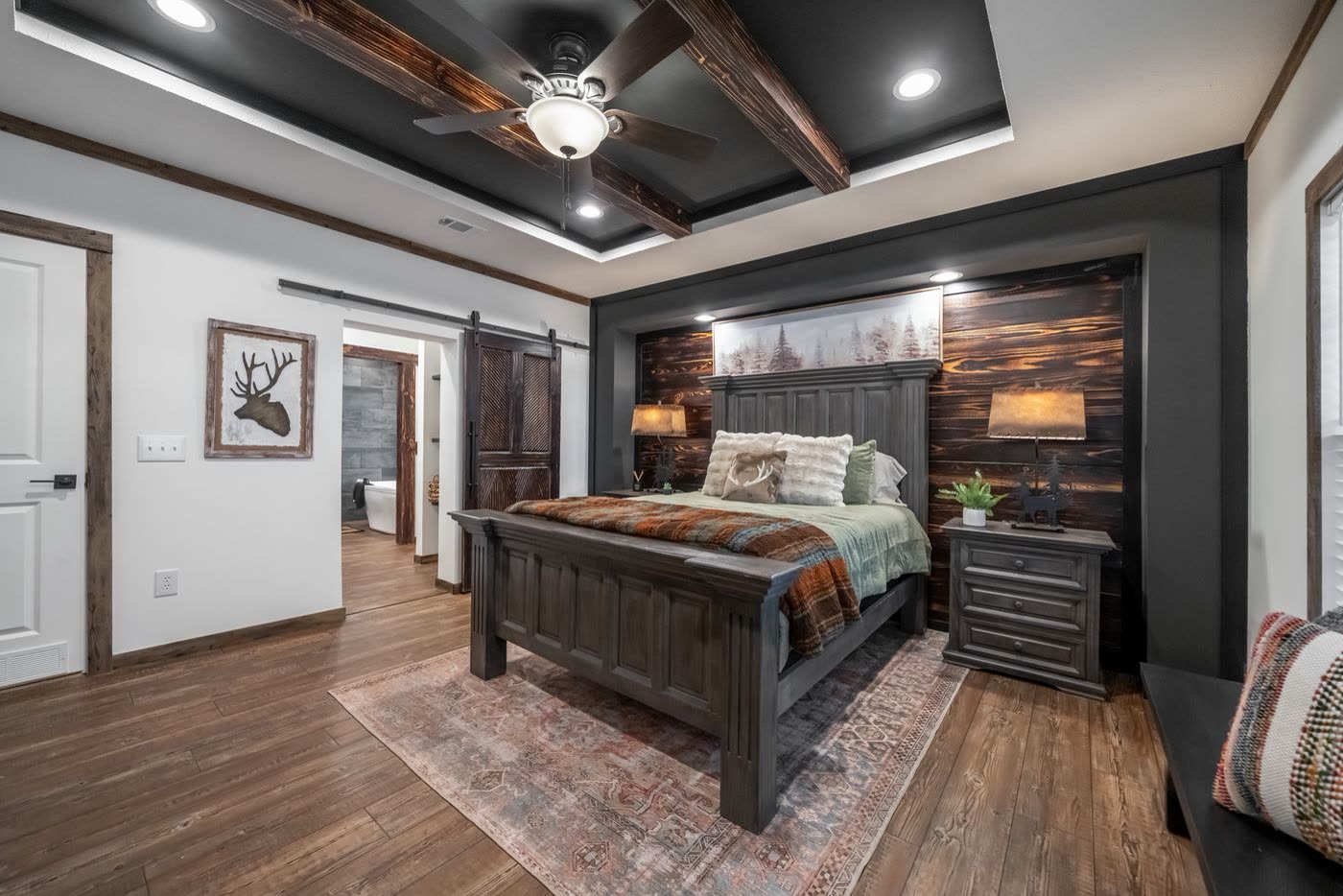 Primary bedroom. Bed and nightstands, barn door to the bath, hall door at left.