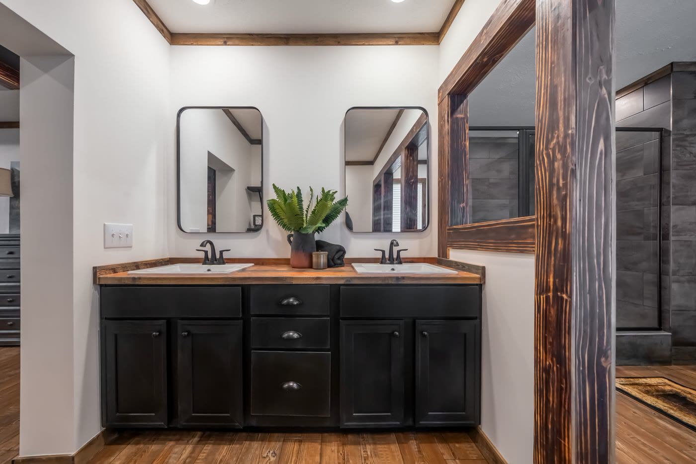 Primary bath. Double vanity with two mirrors, wood-look counter, dark cabinets.