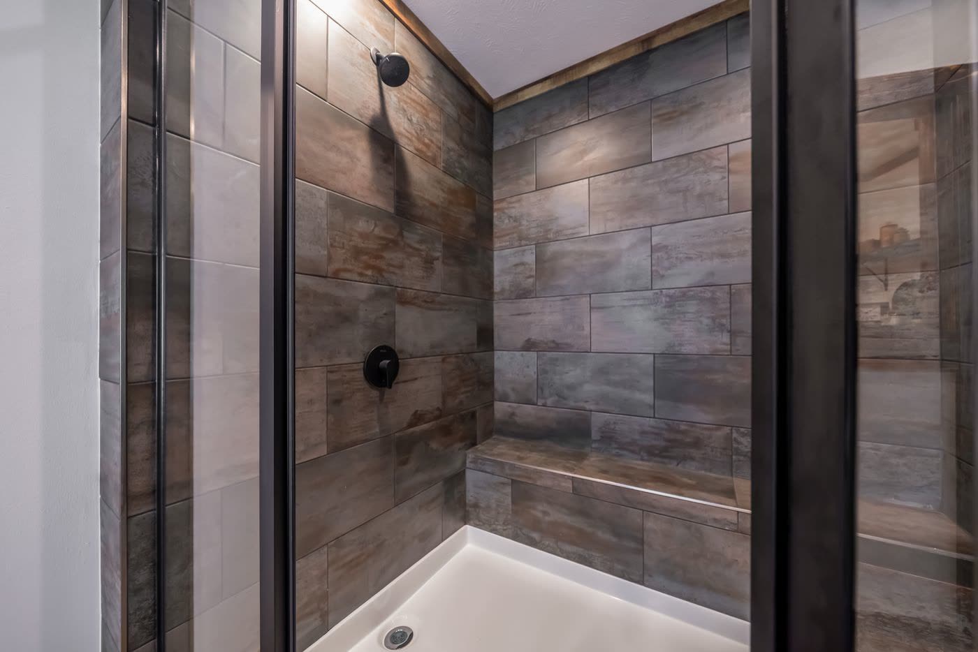 Primary bath. Tiled shower with bench and black fixtures.